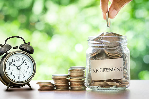 istockphoto-622064048-612x612 Hand putting Coins in glass jar with retro alarm clock for time to money saving for retirement concept